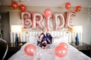 Florida Bride Having Fun Getting Ready Photo, BRIDE Balloons in Rose Pink, Wearing Navy Silk Robe with Red Floral Design at Downtown Tampa Hotel | Tampa Bay Wedding Photographer Lifelong Photography Studio | Tampa Wedding Hair and Makeup Artist Femme Akoi Beauty Studios