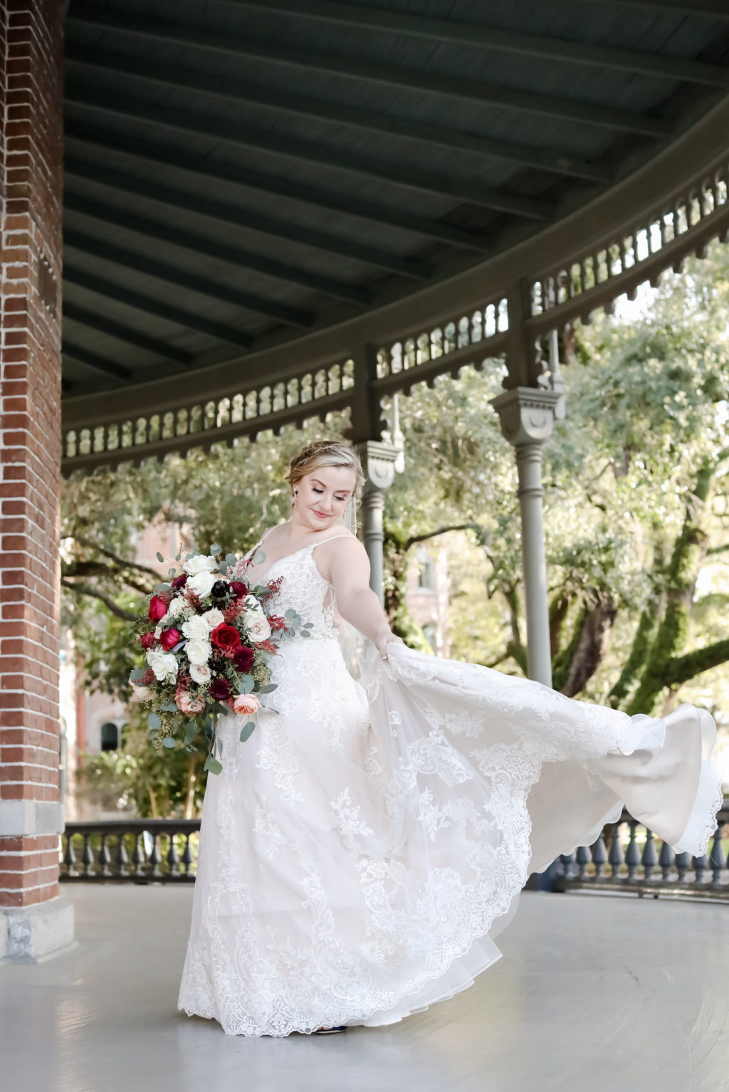 Romantic, Boho Whimsical Inspired Florida Bride in Wedding Dress at Historic University of Tampa UT, Kitty Chen Couture Pera Design, A-Line Ivory Lace Gown with Sultry Low-cut Back, Illusion Lace Fitted Bodice, Bohomeian All Natural Hair and Makeup Style with Braided Updo, Holding Romantic Cascading Rose Bridal Bouquet with Deep Red, Light Ivory, Pink and White Florals with Greenery | Tampa Bay Bridal Boutique CC's Bridal | Florida Wedding Photographer Lifelong Photography Studio | Tampa Heights Hair and Makeup Artist Femme Akoi Beauty | Downtown Tampa Wedding Transportation Skyline Limousine