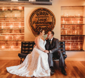 Florida Bride and Groom Romantic Wedding Portrait Inside Historic Venue in Downtown Saint Petersburg, Keep Local Custom Sign, Exposed Brick with Candlelight Lighting, Bride Wearing Blush By Hayley Paige Ivory Delta Gown Style 1751 | Unique Tampa Bay Wedding Venue NOVA 535 in Downtown St. Petersburg