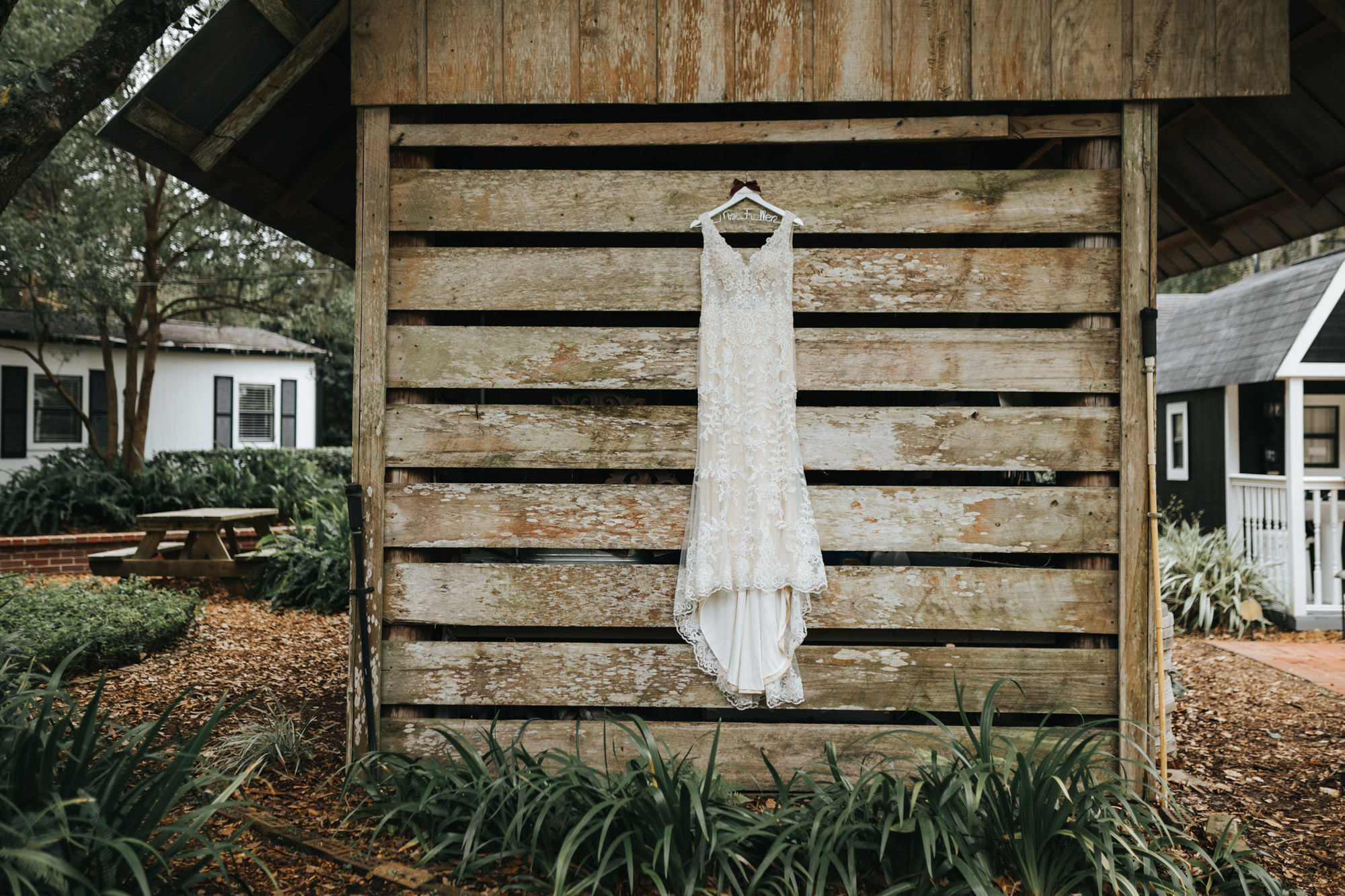 Wedding Dress Hanger Shot | V Neck Champagne Lace Bridal Gown Wedding Dress from Sarasota Dress Shop Truly Forever Bridal | Custom Name Hanger on Rustic Wood Plank Wall