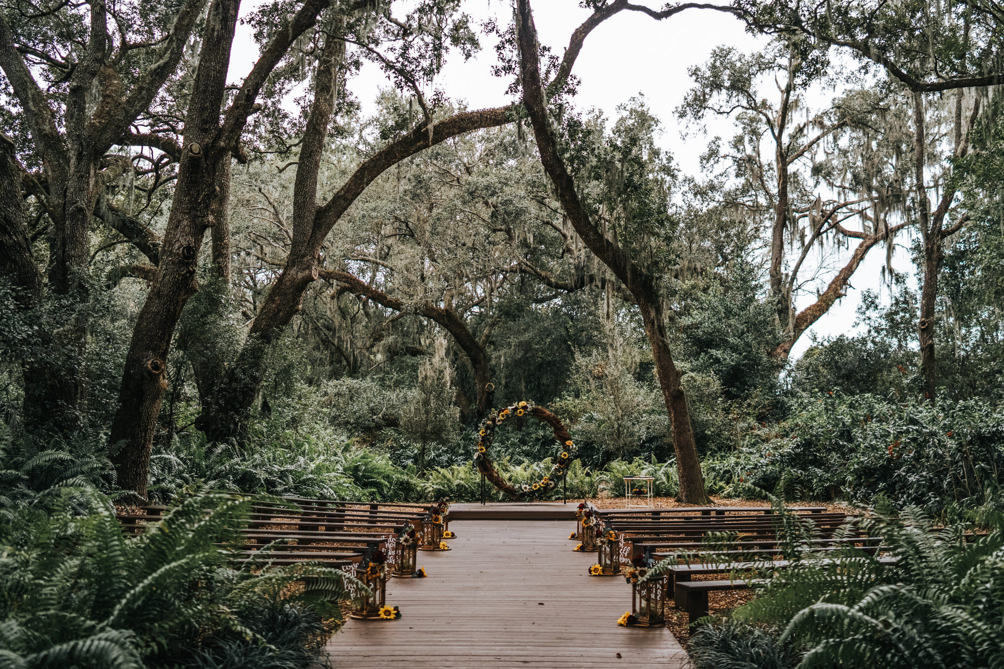 Rustic Dover Burgundy and Yellow Sunflower Outdoor Wedding Ceremony with Wood Benches and Round Grapevine Branch Arch and Lanterns down the Aisle