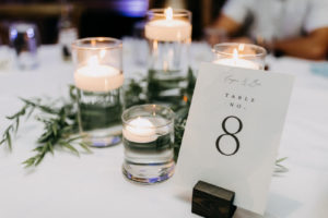 Classic Wedding Reception Decor, White and Black Font Table Number Signage on Wooden Pedestal, Floating Candles, Greenery Wreath | Tampa Bay Wedding Photographer Amber McWhorter Photography