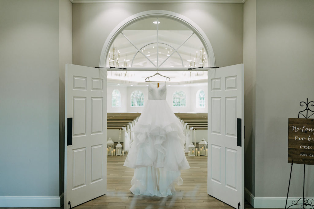 Horsehair Trim Full Ruffle Skirt V Neckline Wedding Dress Hanging in Safety Harbor Wedding Venue Harborside Chapel | Tampa Bay Wedding Photographer Amber McWhorter Photography