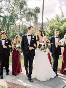 Outdoor Fall Tampa Wedding Party Portrait | V Back Embroidered Illusion Panel Allure Couture Designer Wedding Dress Bridal Gown with Long Cathedral Veil | Fall Wedding Bridal and Bridesmaid Bouquets with Red and White Roses and Eucalyptus Greenery | Long Burgundy Maroon Red Chiffon Off The Shoulder Bridesmaid Gown Dresses by David's Bridal | Groom and Groomsmen in Classic Black Suit Tux with Bow Tie