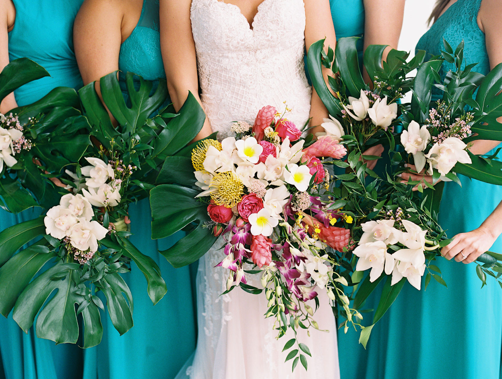 Tampa Bay Bride in Lace Wedding Dress with Bridesmaids in Mix and Match Teal Dresses Holding Tropical Floral Bouquets, Tropical Pink Ginger, Yellow Pincushion Protea, Purple Orchid, Greenery, Monstera Palm Tree Leaves Flowers