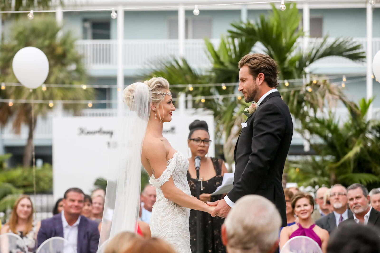 Sarasota Bride and Groom Exchange Vows At Tropical Inspired Outdoor Ceremony at Bali Hali Resort at Anna Marie Island, Bride in Vintage Lace Off the Shoulder Wedding Dress with Crystal Headpiece with Long Veil | Sarasota Wedding Planner Kelly Kennedy Weddings | Florida Wedding Photographer Lifelong Photography Studio