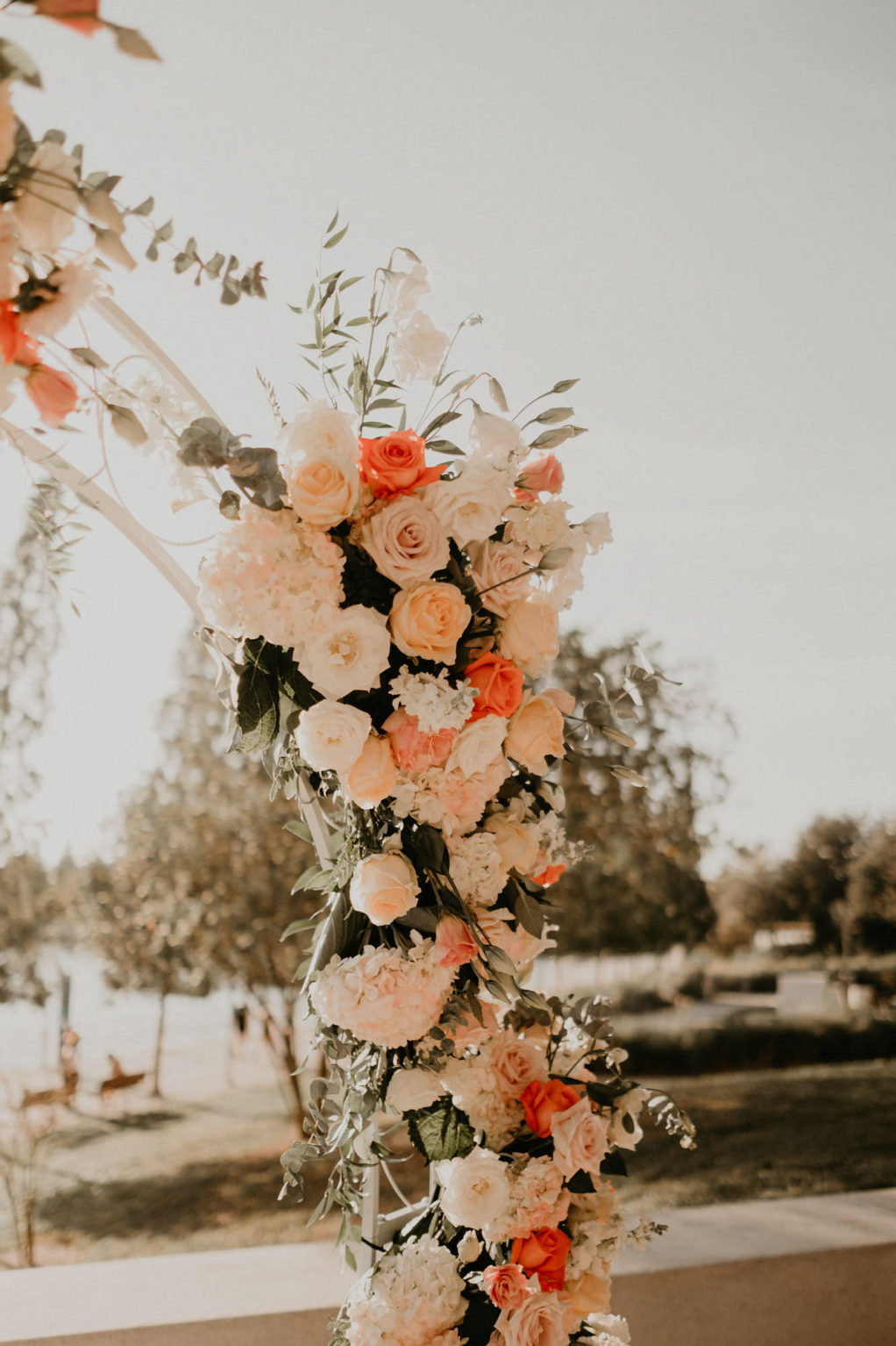 Outdoor Wedding Ceremony Arch Floral Arrangement with Peach Salmon Coral Roses White Hydrangea and Eucalyptus Greenery