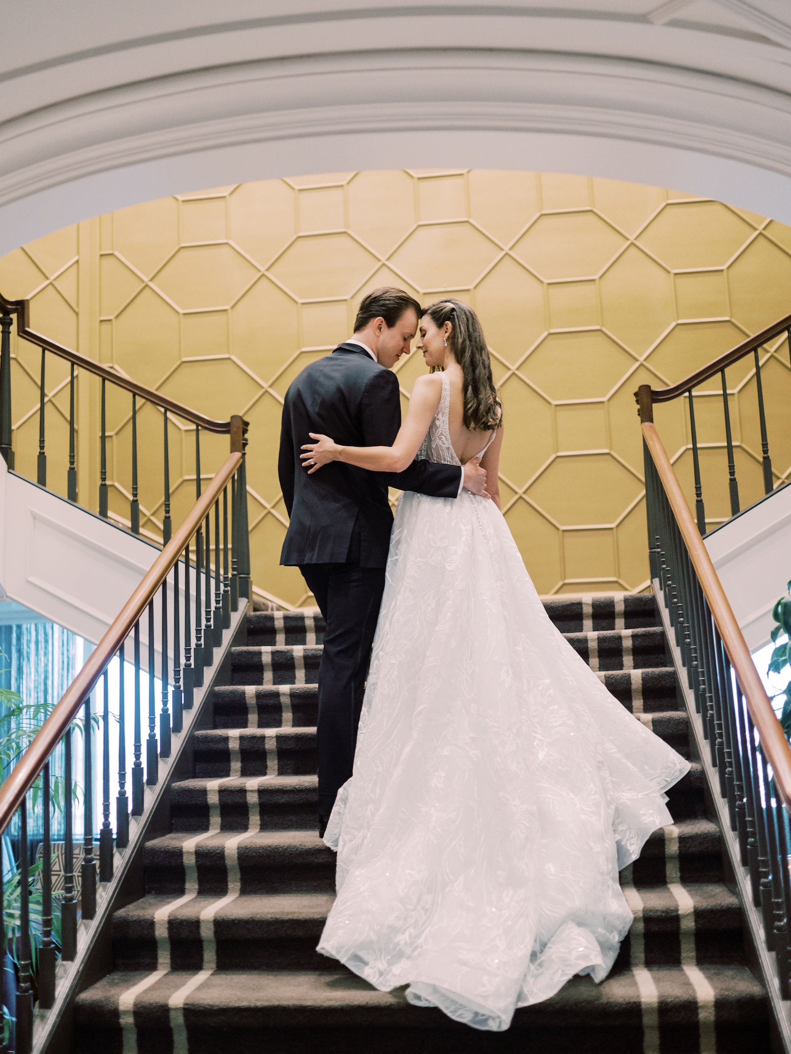 Indoor Bride and Groom Portrait at Downtown Tampa Wedding Venue The Tampa Club Staircase | V Back Embroidered Illusion Panel Allure Couture Designer Wedding Dress Bridal Gown | Groom in Classic Black Suit Tux with Bow Tie