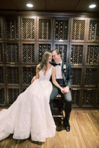 Indoor Bride and Groom Portrait at Downtown Tampa Wedding Venue The Tampa Club Wine Room | V Neck Embroidered Illusion Panel Allure Couture Designer Wedding Dress Bridal Gown | Groom in Classic Black Suit Tux with Bow Tie