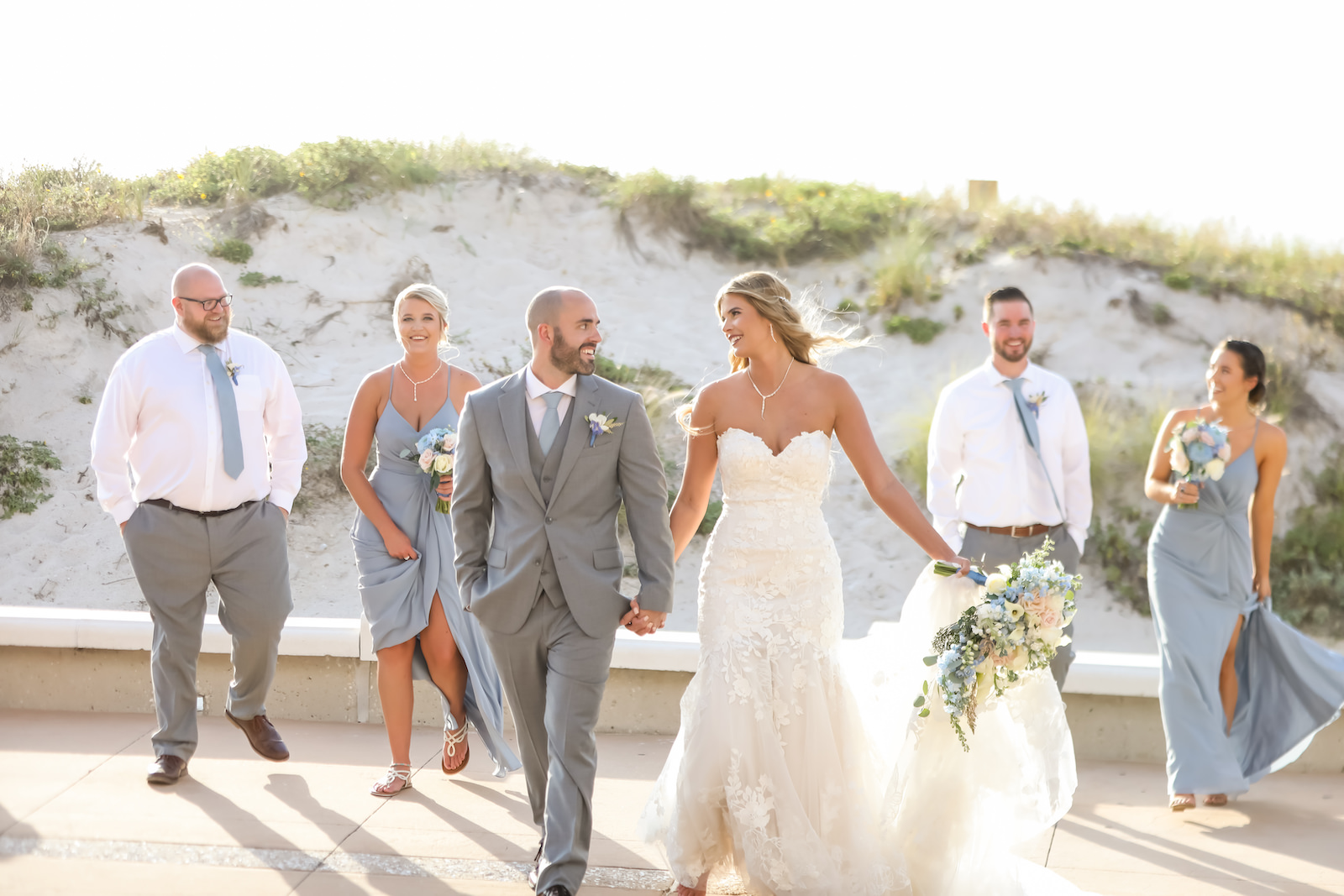 Outdoor Wedding Party Portrait at Clearwater Beach | Groom Wearing Silver Grey Suit | Strapless Lace Sweetheart Mermaid Wedding Dress Bridal Gown | Dusty Blue Grey Bridesmaid Dresses