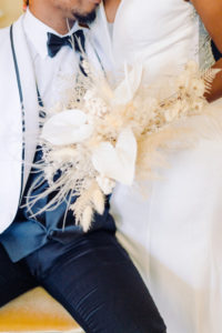 Modern and Boho Groom in White and Black Tuxedo, Bride in Classic Dress Holding Dried Unique White Floral, Feathers and Foliage Bouquet | Tampa Bay Wedding Planner, Designer, Florist John Campbell Weddings