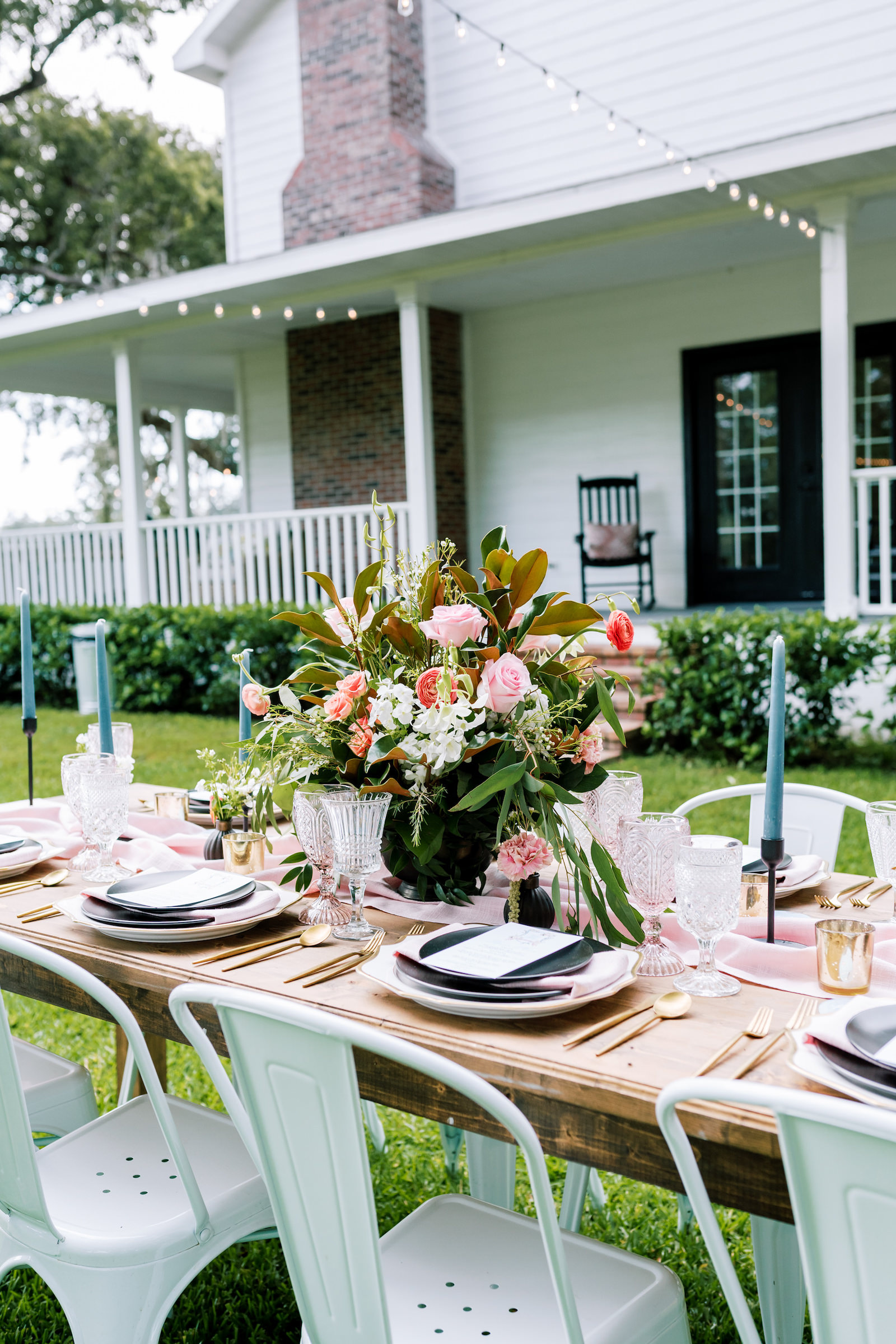 Southern Elegant Inspired Florida Outdoor Wedding Reception, Long Wooden Feasting Table with Dark Blue Place Setting, Gold Flatware, Pink Burlap Linens, Tall Blue Candelabras, Low Floral Centerpiece with Pink Roses, Orange Florals, and Magnolia Leaf Greenery | Tampa Bay Wedding Planner EventFull Weddings