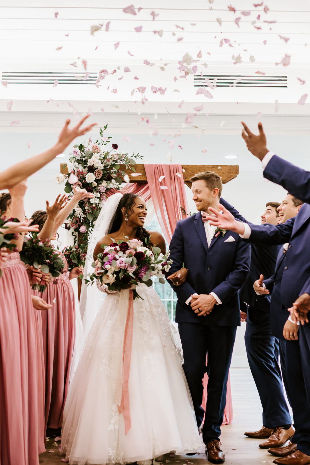 Indoor Church Wedding Rose Petal Toss at St. Pete Wedding Venue Harborside Chapel | Blush Pink Dusty Rose Mauve Bridesmaid Dresses | Groom and Groomsmen in Navy Blue Suit | Tulle and Lace Ballgown Wedding Dress
