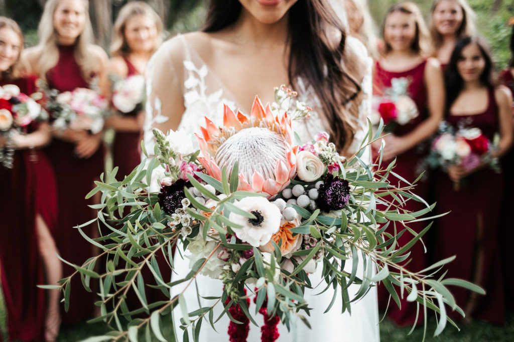 St. Petersburg Bride Holding Exotic Tropical Inspired Bridal Bouquet with Bright Pink King Protea, White, Dark Purple, Burgundy, Wine Florals with Greenery | Florida Wedding Florist Posies Flower Truck | Tampa Bay Wedding Planner John Campbell Weddings
