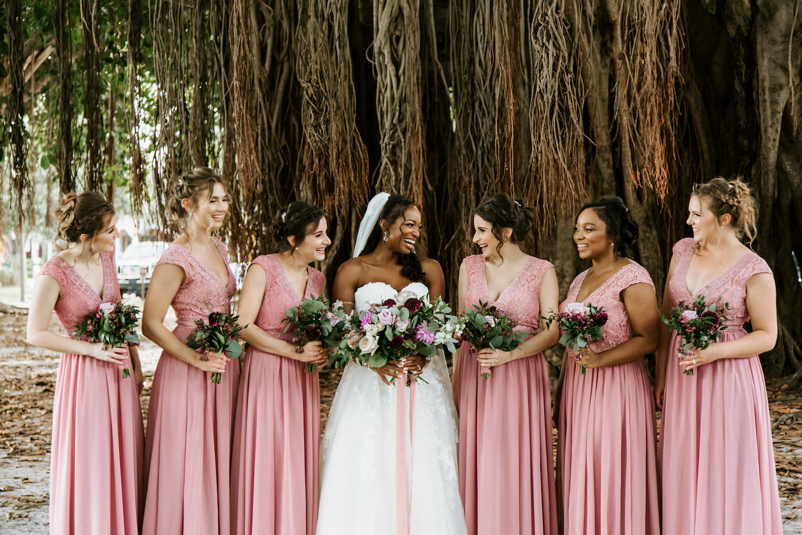 Bride and Bridesmaids Outdoor Portrait Shot in Downtown St. Pete | Blush Pink Dusty Rose Mauve Long Lace and Chiffon Bridesmaid Dresses by JJ's House | Natural Loose Bouquets with Pink and Maroon Roses and Eucalyptus Greenery