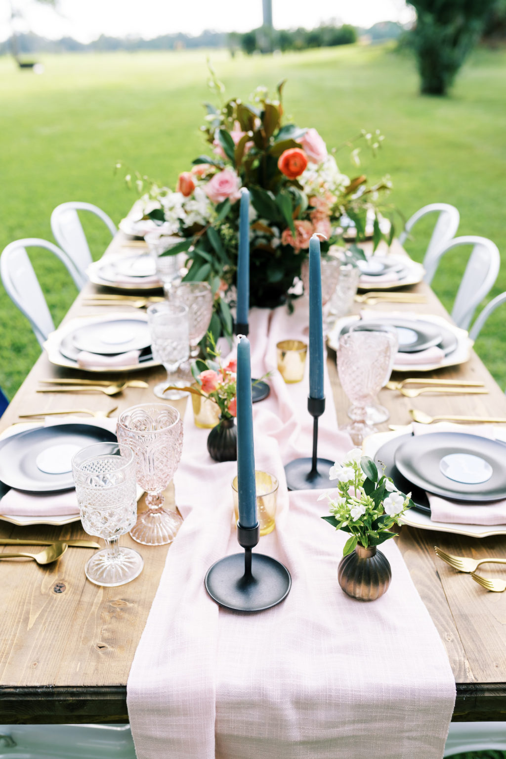 Southern Elegant Inspired Florida Outdoor Wedding Reception, Long Wooden Feasting Table with Dark Blue Place Setting, Gold Flatware, Pink Burlap Linens, Tall Blue Candelabras, Low Floral Centerpiece with Pink Roses, Orange Florals, and Magnolia Leaf Greenery | Tampa Bay Wedding Planner EventFull Weddings | Florida Wedding Linen Rentals Over The Top Linen Rentals