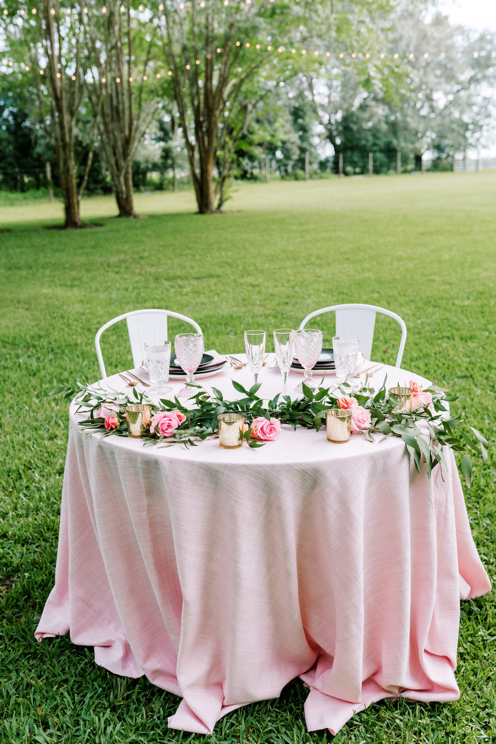Vintage Inspired Outdoor Florida Wedding Reception, Sweetheart Table with Pink Linens, Magnolia Leaves as Greenery with Bright Pink Roses, Multicolored Goblets with Outdoor String Lighting | Florida Wedding Rentals Over The Top Linen Rentals | Tampa Bay Luxury Wedding Planners EventFull Weddings