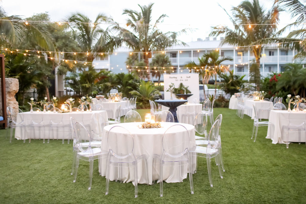 Romantic, Modern Outdoor Florida Wedding Reception at Bali Hai Beachfront Resort Anna Marie Island, Long Feasting Tables and Round Tables with Acrylic Ghost Chair Rentals, Low Floral Centerpieces with Candles, Stringlighting, | Sarasota Wedding Planner Kelly Kennedy Weddings | Tampa Bay Wedding Photographer Lifelong Photography Studio