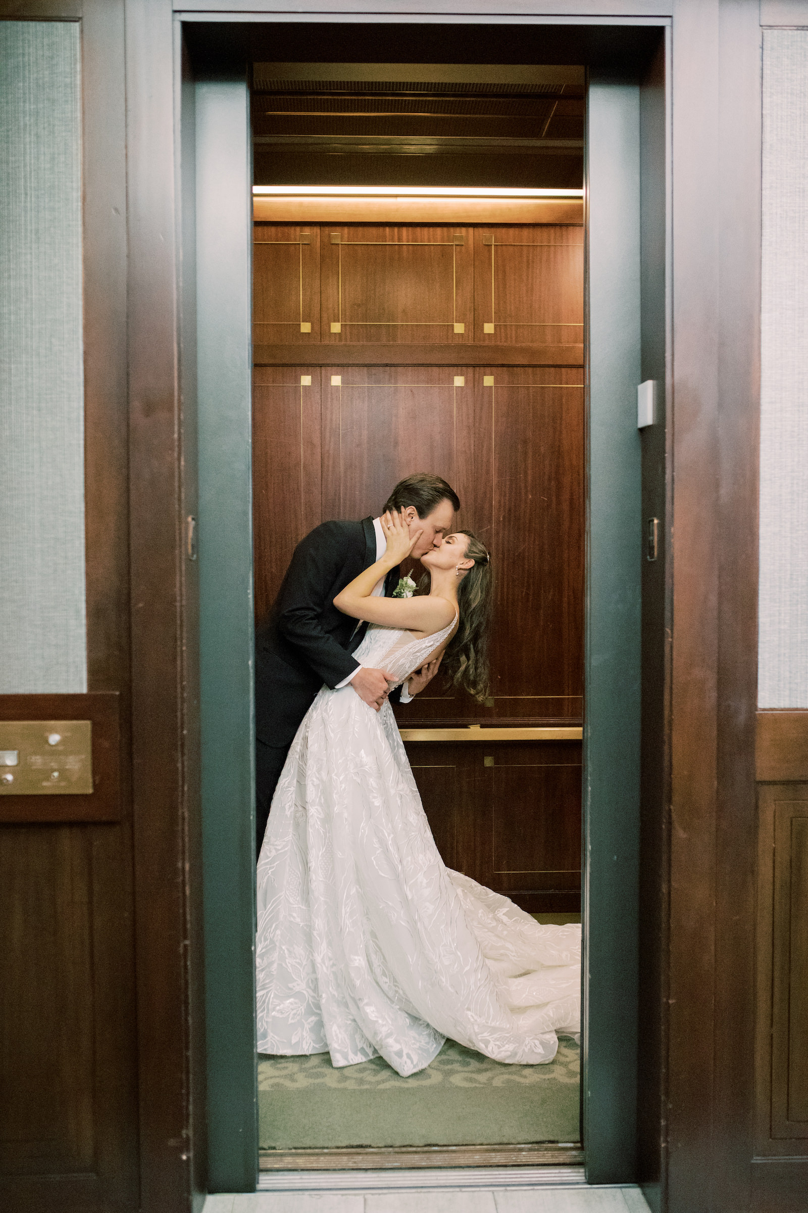 Indoor Bride and Groom Portrait at Downtown Tampa Wedding Venue The Tampa Club Elevator | V Neck Embroidered Illusion Panel Allure Couture Designer Wedding Dress Bridal Gown | Groom in Classic Black Suit Tux with Bow Tie