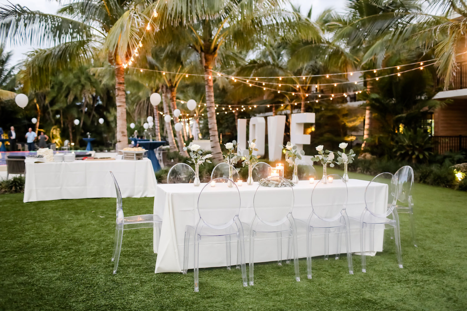 Romantic, Modern Outdoor Florida Wedding Reception at Bali Hai Beachfront Resort Anna Marie Island, Long Feasting Tables, Acrylic Ghost Chair Rentals, Low Floral Centerpieces with Candles, String lighting, Oversized Large LOVE Letters | Sarasota Wedding Planner Kelly Kennedy Weddings | Tampa Bay Wedding Photographer Lifelong Photography Studio