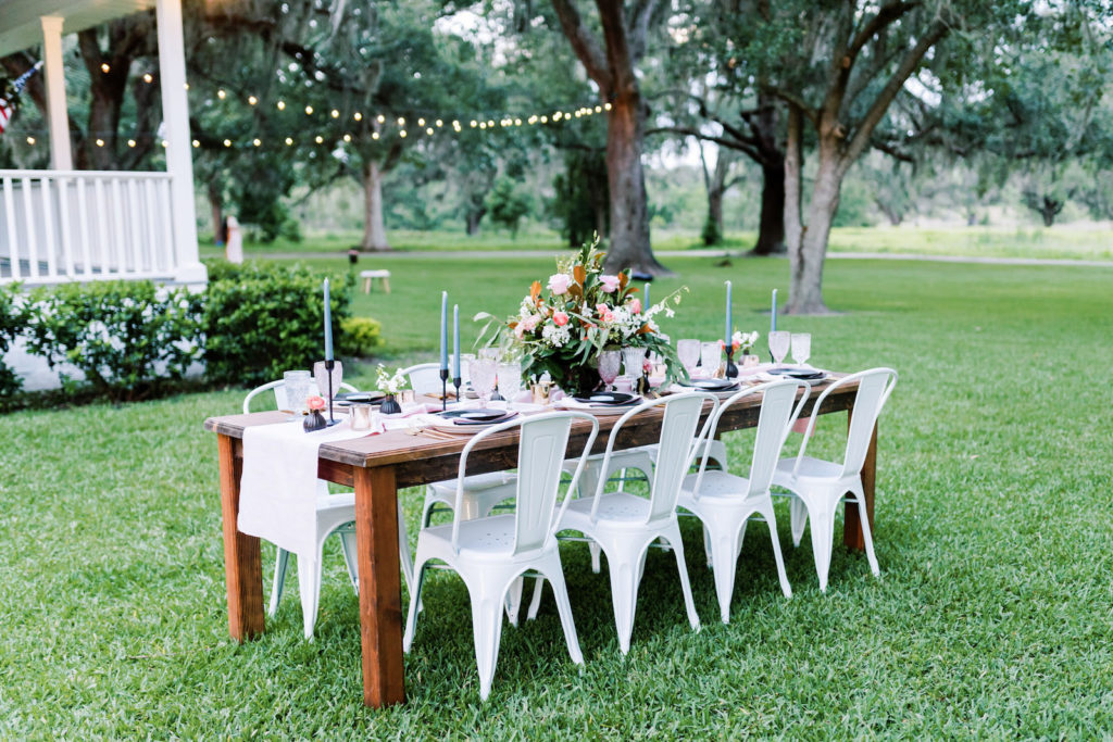 Southern Elegant Inspired Florida Outdoor Wedding Reception, Wood Table with Dark Blue Place Setting, Gold Flatware, Pink Burlap Linens, Multicolored Glass Goblets, Floral Centerpiece with Magnolia Leaves | Tampa Bay Wedding Planner EventFull Weddings | Florida Wedding Rentals Over The Top Linens | Two Sisters Ranch Dade City Florida