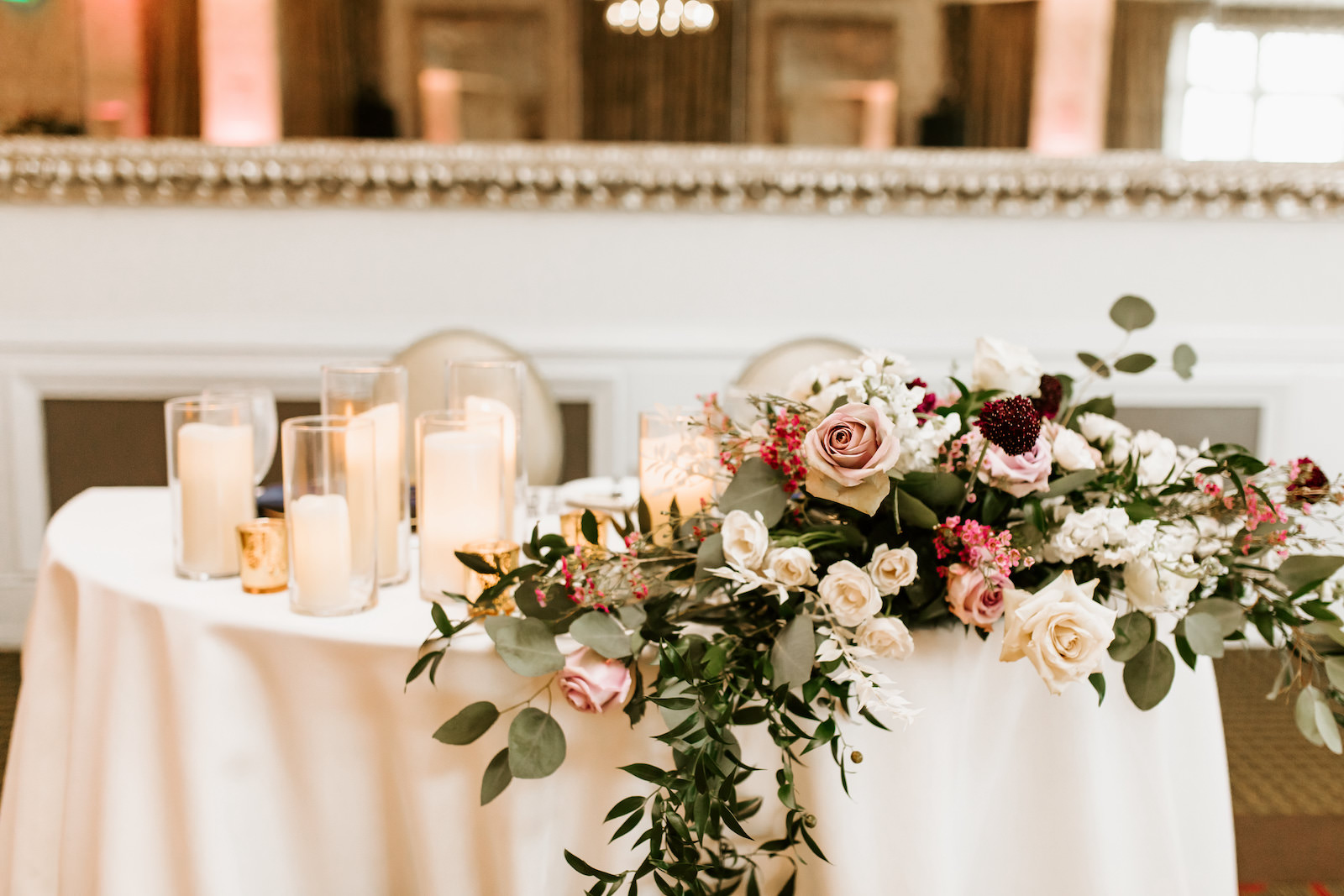 Wedding Sweetheart Table with Glass Cylinder Pillar Candles and Gold Mercury Glass Votives with Natural Loose Cascading Centerpiece of Eucalyptus Greenery and Pink and Cream Roses