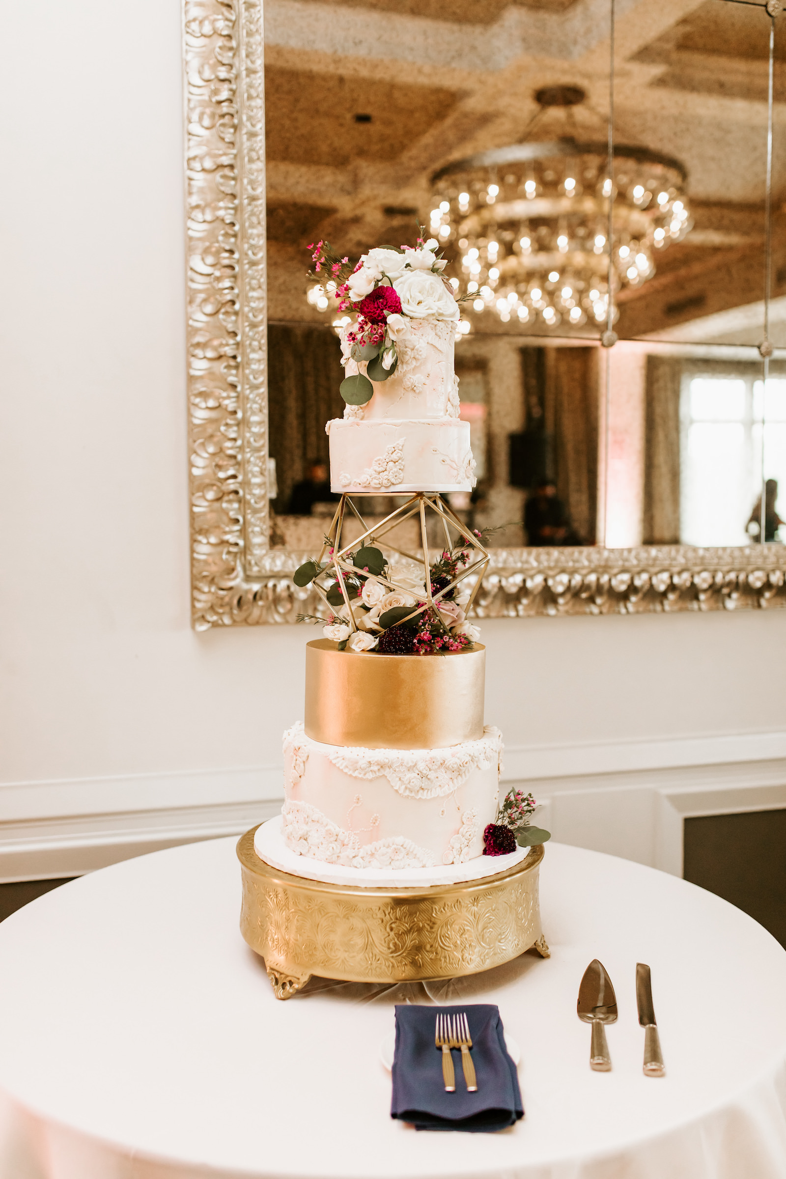 Four Tier Wedding Cake with Gold Geometric Orb Layer on Gold Ornate Stand by Tampa Cake Baker The Artistic Whisk | Piped Lace Buttercream Fondant Victorian Fancy Wedding Cake with White and Red Fresh Flowers Roses and Greenery