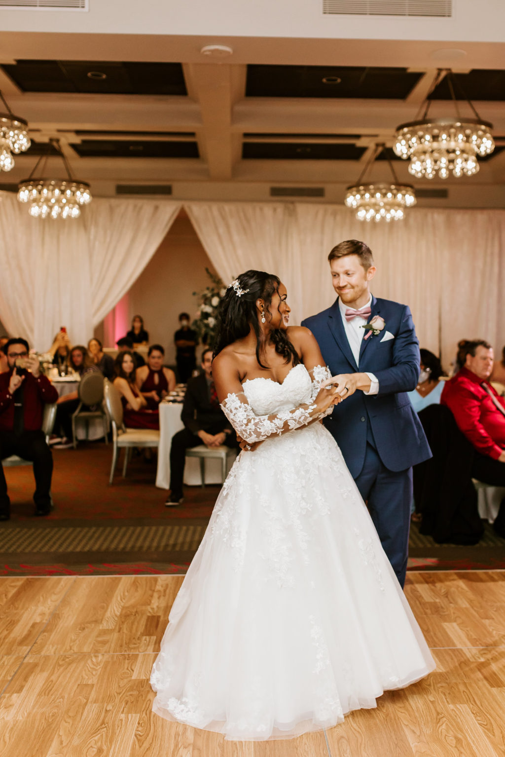 Bride and Groom First Dance Photo | Indoor Hotel Reception at St. Pete Wedding Venue The Birchwood | Tulle and Lace Ballgown Wedding Dress with Illusion Lace Sleeves and Sweetheart Neckline by Stella York | Groom Wearing Navy Blue Suit