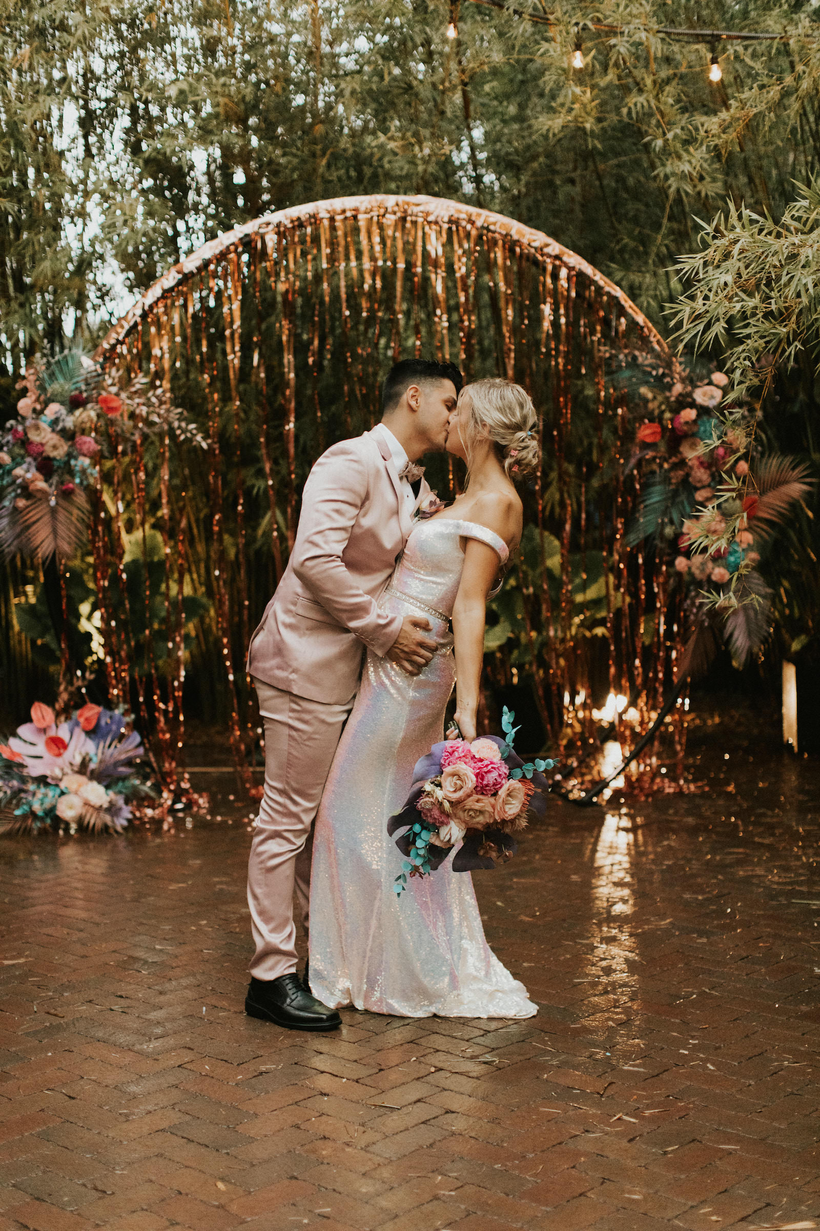 Iridescent Pastel 90's Wedding Inspiration | Wedding Arch Backdrop with Rose Gold Tinsel Curtain and Pastel Flower Arrangements with Painted Leaves | Bride and Groom Portrait with Blush Pink Suit and Shimmer Silver Wedding Dress | Downtown St. Pete Wedding Venue NOVA 535