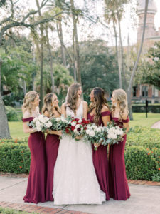 Outdoor Bride and Bridesmaids Portrait | V Back Embroidered Illusion Panel Allure Couture Designer Wedding Dress Bridal Gown with Long Cathedral Veil | Fall Wedding Bridal and Bridesmaid Bouquets with Red and White roses and Eucalyptus Greenery | Long Burgundy Maroon Red Chiffon Off The Shoulder Bridesmaid Gown Dresses by David's Bridal | Femme Akoi Beauty Studio