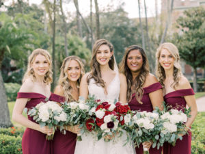 Outdoor Bride and Bridesmaids Portrait | V Back Embroidered Illusion Panel Allure Couture Designer Wedding Dress Bridal Gown with Long Cathedral Veil | Fall Wedding Bridal and Bridesmaid Bouquets with Red and White roses and Eucalyptus Greenery | Long Burgundy Maroon Red Chiffon Off The Shoulder Bridesmaid Gown Dresses by David's Bridal | Femme Akoi Beauty Studio