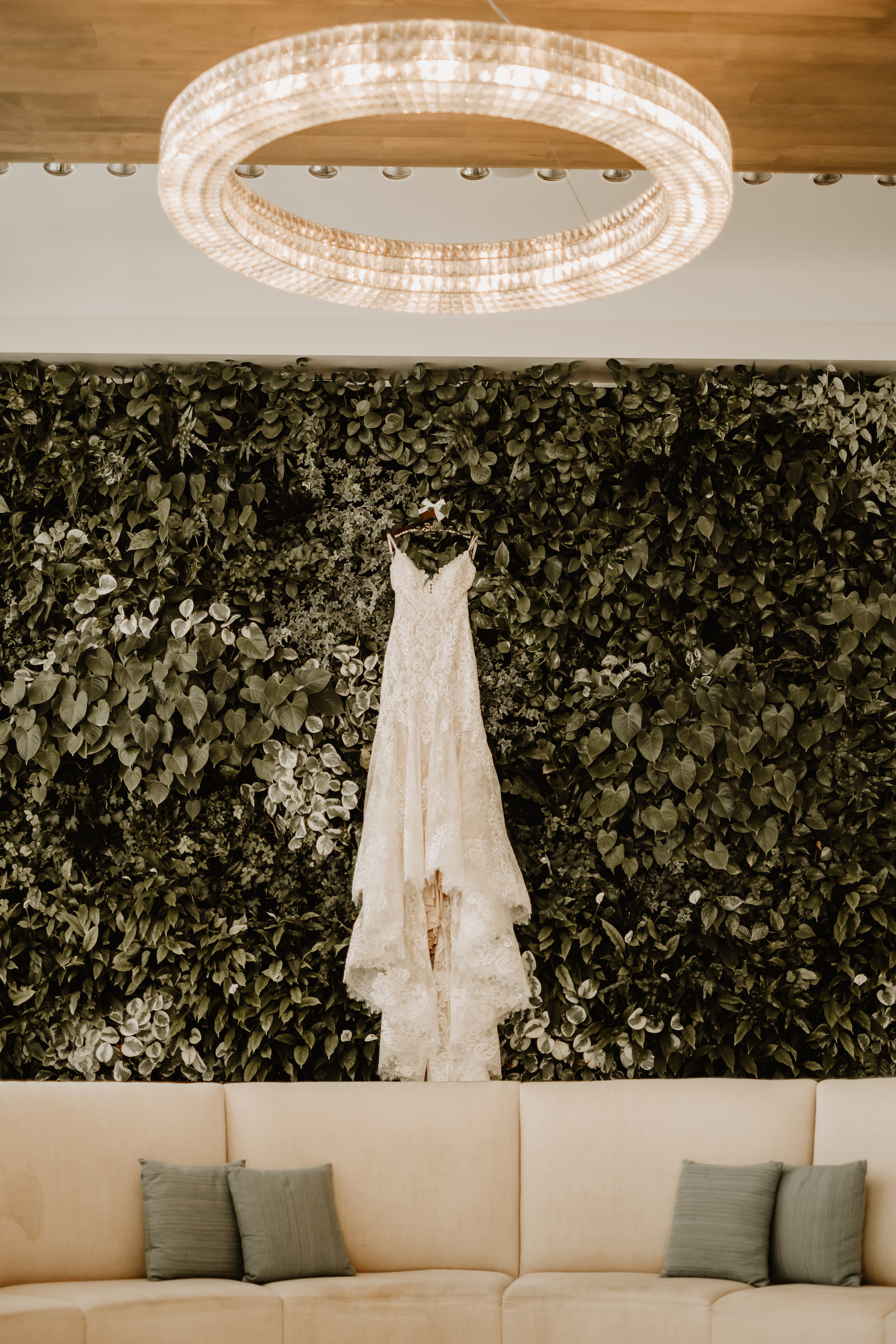 Wedding Dress Hanger Shot on Greenery Hedge Wall Backdrop | Allure Bridal Lace V Neck Spaghetti Strap Sheath Bridal Gown