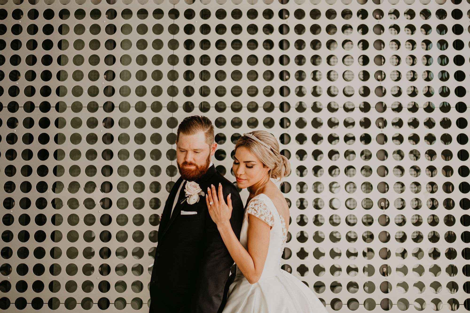 Bride and Groom Portrait with Polka Dots Pattern Wall Backdrop | Groom in Classic Black Suit Tux | Low Back Ballgown Wedding Dress by Anomalie