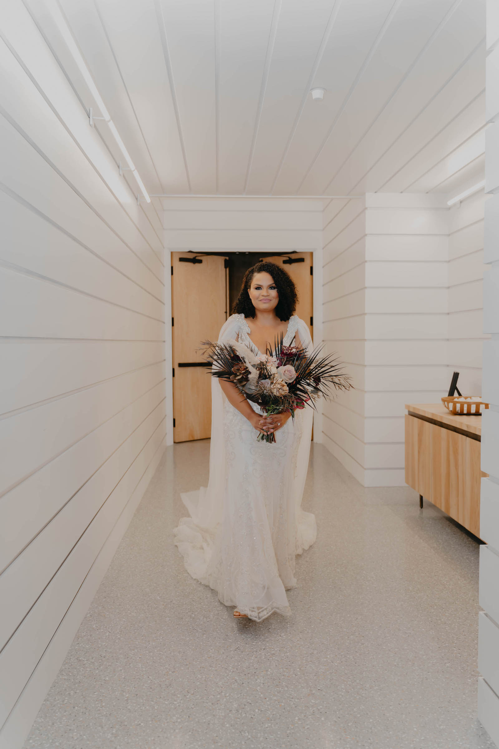 Indoor Bridal Portrait in Tampa Wedding Venue Hyde House | Illusion Lace Embroidered Beaded V Neck Wedding Dress Bridal Gown with Sheer Tulle Cape Sleeves by Designer Amalia Carrara Bridal | Boho Moody Wild Bridal Bouquet with Deep Green Leaves, Cafe au Lait Roses and Deep Red Burgundy Scabiosa and Orchids