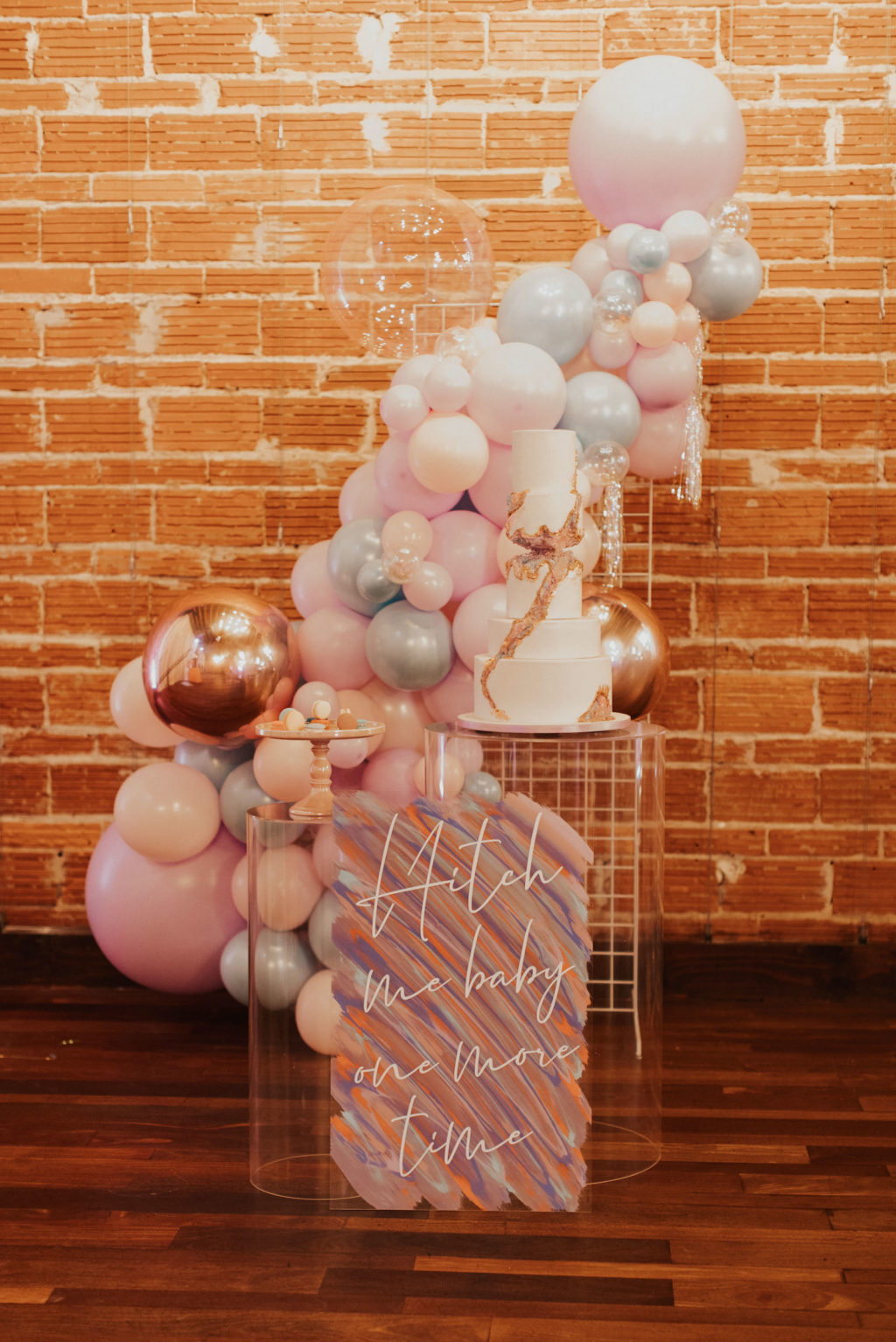 Iridescent Pastel 90's Wedding Inspiration | Pastel Pink Peach Silver Rose Gold Balloon Installation | Round Five Tier Fondant Wedding Cake with Iridescent Geod Sugar Crystals and Rainbow Macarons on Clear Acrylic Table