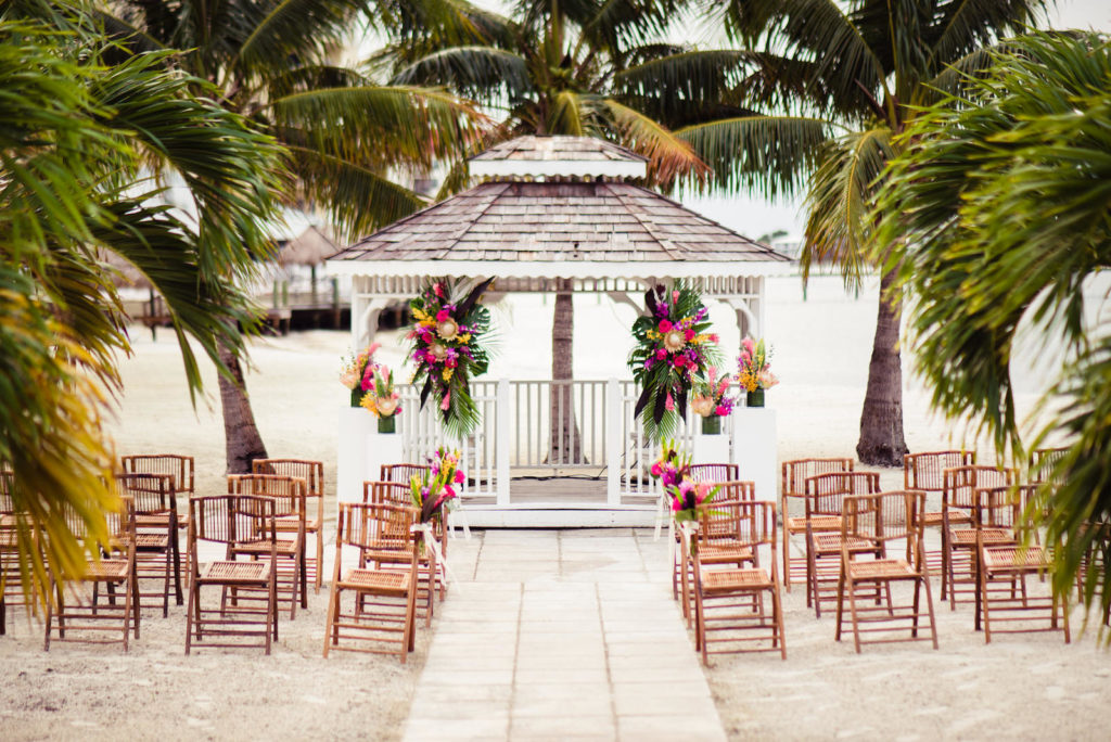 Vibrant Pink, Yellow, and Green Tropical Beach Wedding Ceremony with Bamboo Chairs | St. Petersburg Wedding Venue Isla Del Sol Yacht and Country Club