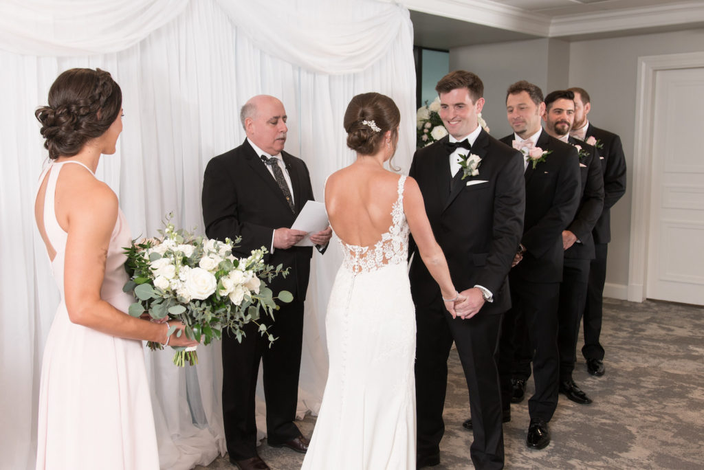 Downtown Tampa Wedding Ceremony at Tampa Wedding Venue The Tampa Club | Groom and Groomsmen Wearing Classic Black Suit Tux | Stella York Designer Illusion Lace V Neck Sheath Chiffon Satin Wedding Dress Bridal Gown | White Rose and Eucalyptus Greenery Bouquet | Carrie Wildes Photography