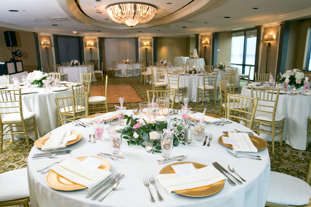 Indoor Wedding Reception at Downtown Tampa wedding Venue The Tampa Club | White Reception Table Linens with Gold Chiavari Chairs and Chargers and Centerpieces of White Hydrangea and White and Blush Pink Roses with Eucalyptus Greenery and Floating Candles | Carrie Wildes Photography