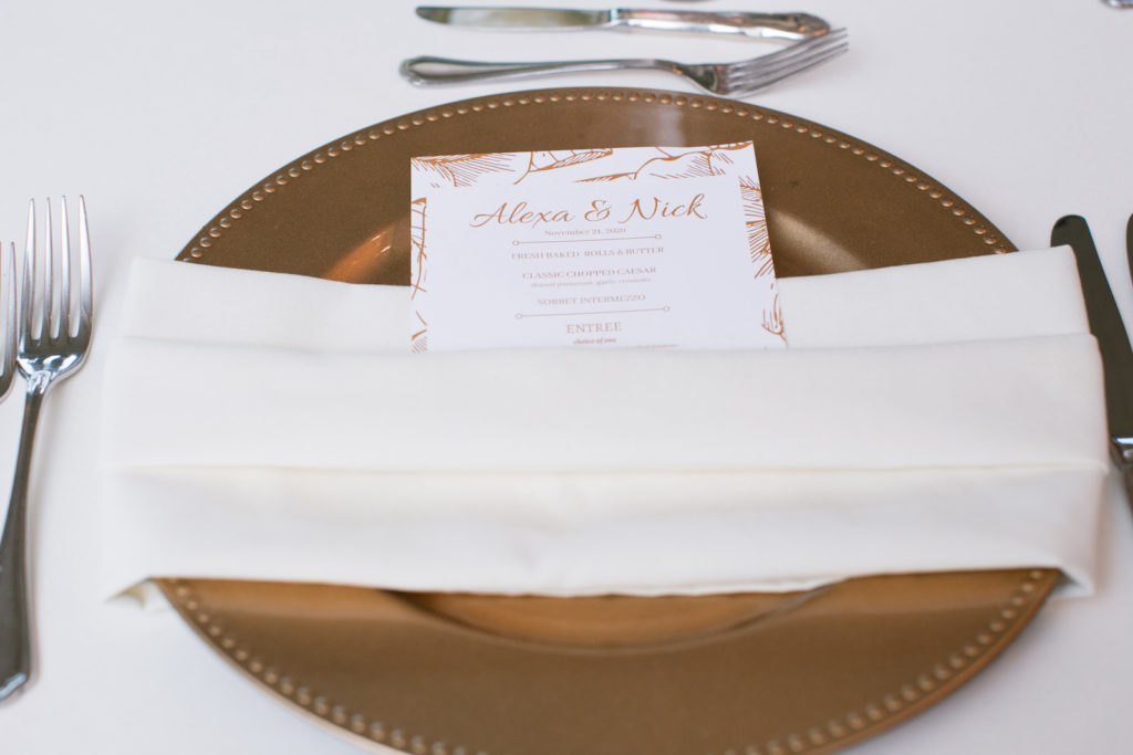 Wedding Place Setting with Gold Charger Plate and White Napkin Belly Band with Menu Card Featuring Gold Floral Border