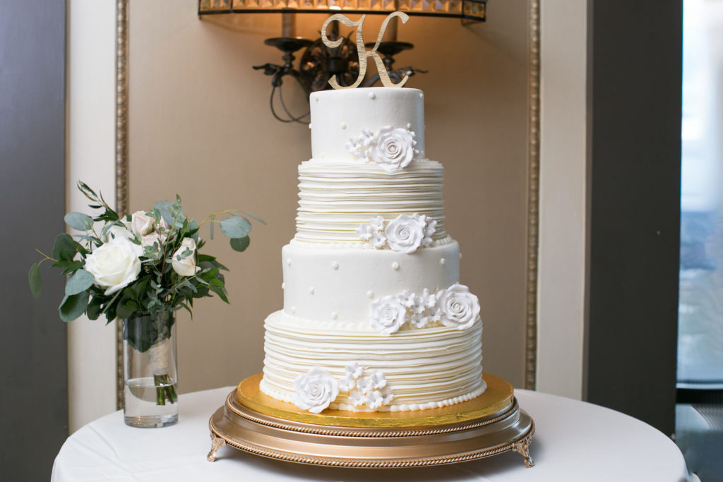 Four Tier wedding Cake with Ribbed Textured Buttercream and Polka Dots with White Sugar Flowers by Publix | Round Gold Cake Stand and Gold Monogram Cake Topper