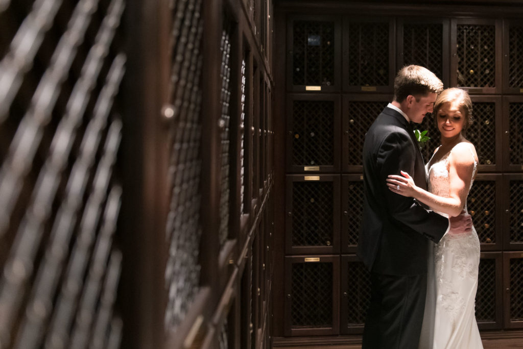 Downtown Tampa Wedding Bride and Groom Portrait at Tampa Wedding Venue The Tampa Club Wine Cellar Room | Groom Wearing Classic Black Suit Tux | Stella York Designer Illusion Lace V Neck Sheath Chiffon Satin Wedding Dress Bridal Gown | Carrie Wildes Photography