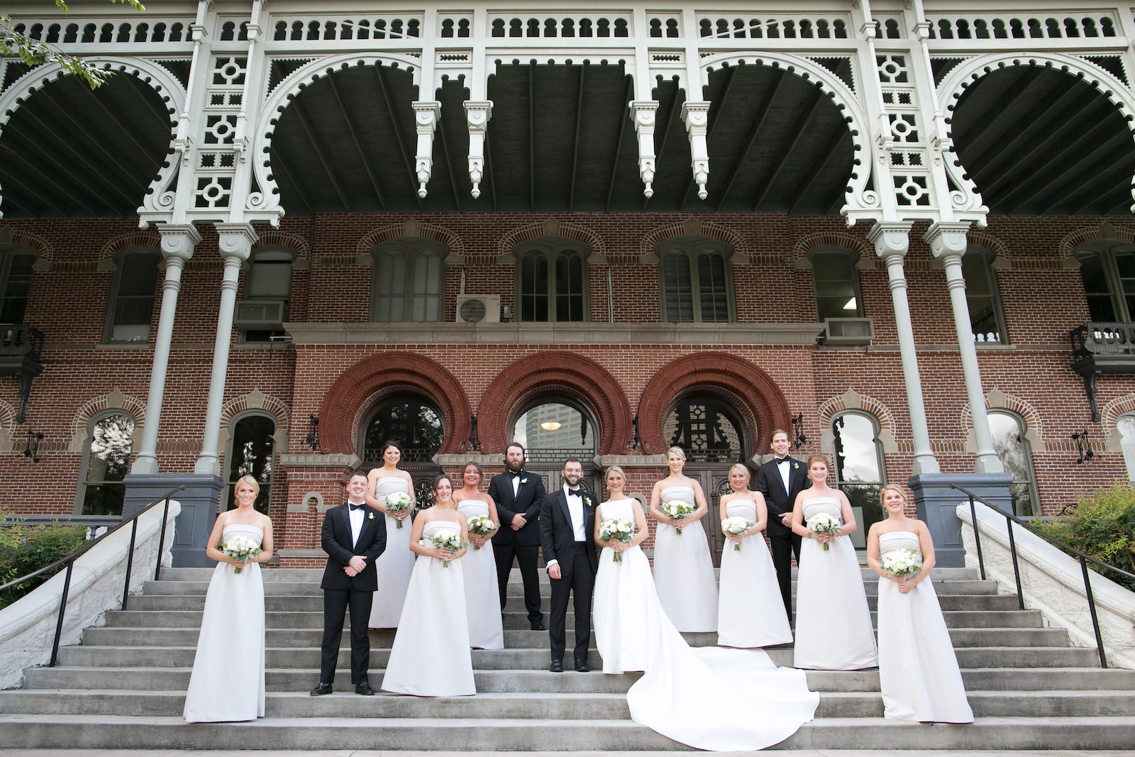 Wedding Party Outdoor Portrait in Downtown Tampa at Plant Museum UT | Bateau Neck Mikado Satin Martina Liana Simple Elegant Wedding Dress with Buttons Down Back | Groom and Groomsmen in Classic Black Tux | Neutral White Rose and Greenery Bouquets | Strapless Taupe Neutral Bridesmaid Dresses by Amsale | Carrie Wildes Photography