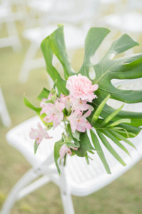 Tropical Wedding Ceremony Decor, Monstera Leaves and Palm Fronds, Pink Flowers Arrangement on Chairs | Tampa Bay Wedding Planner Coastal Coordinating