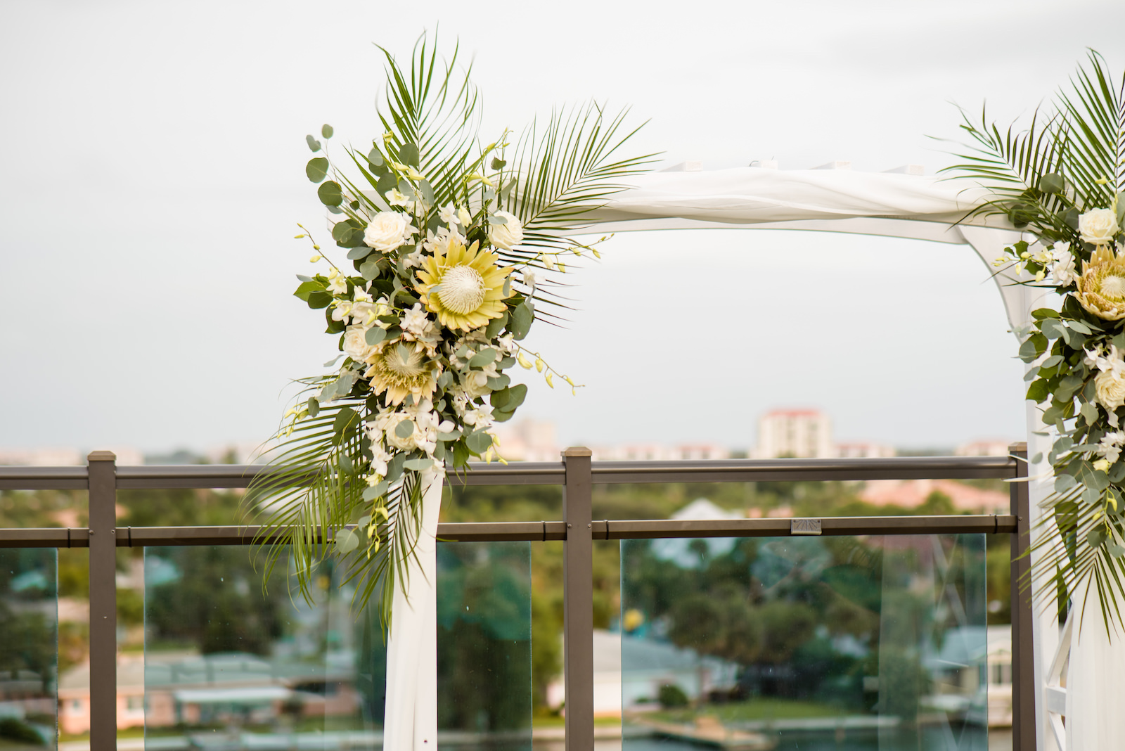 Neutral Boho Tropical Wedding Ceremony Decor, Lush Floral Arrangement on Arch, King Proteas, White Roses and Orchids, Palm Fronds, Eucalyptus | Tampa Bay Wedding Planner Perfecting the Plan | Waterfront St. Pete Wedding Venue The Hotel Zamora | Wedding Florist Iza's Flowers