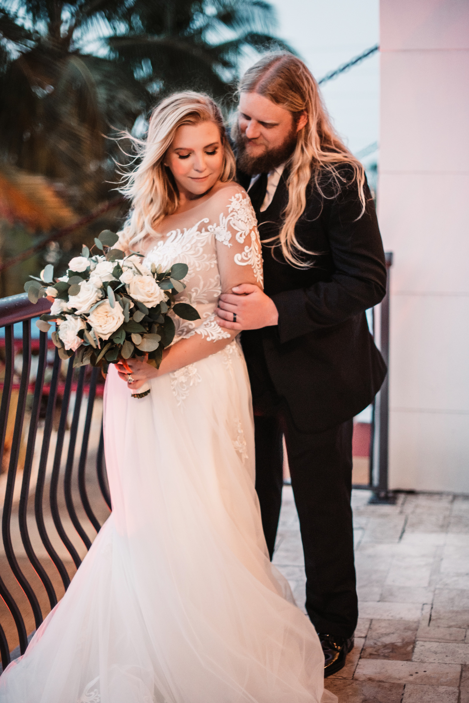 Tampa Bride Wearing Lace and Illusion Long Sleeve Wedding Dress Holding Neutral White Roses and Eucalyptus Floral Bouquet and Groom in Black Suit | St. Pete Wedding Venue The Hotel Zamora | Wedding Florist Iza's Flowers