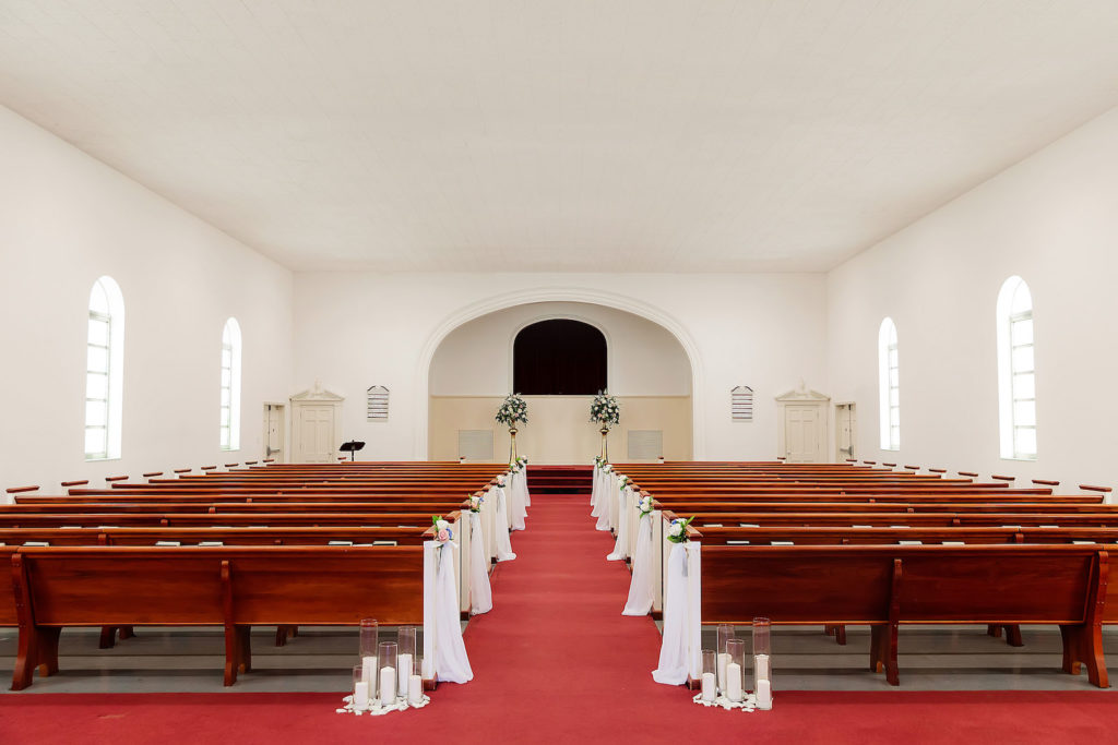 Traditional Tampa Church Wedding Ceremony with Wood Pews and White Ribbon Aisle Markers with Candles