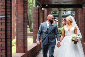 Outdoor Bride and Groom Portrait | Long Cathedral Veil | A Line Ballgown Tulle V Neck Lace Wedding Dress by Hayley Paige Designer | Groom Wearing Classic Charcoal Grey Suit