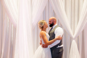 Indoor Bride and Groom Portrait in front of Swag Pipe and Drape Fabric Wall Backdrop