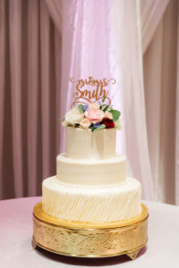 Three Tier Fondant Wedding Cake with Ruffles and Fresh Flowers Roses on Round Ornate Gold Stand by Publix | Die Cut Gold Last Name Wedding Cake Topper