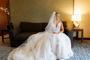 Indoor Bridal Portrait on Sofa | Long Cathedral Veil | A Line Ballgown Tulle V Neck Lace Wedding Dress by Hayley Paige Designer